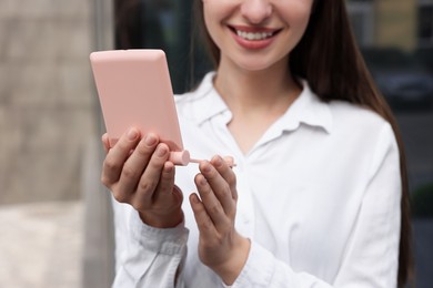 Photo of Young woman looking at herself in cosmetic pocket mirror outdoors, closeup