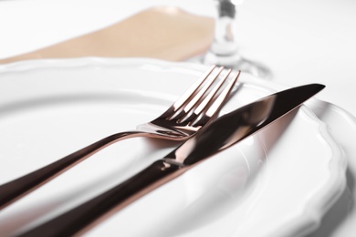 Plates with golden cutlery on table, closeup