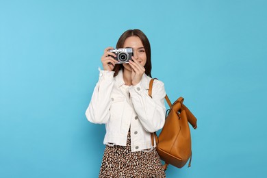Photo of Young woman with camera taking photo on light blue background. Interesting hobby