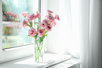 Glass vase with beautiful flowers on window sill in room, space for text
