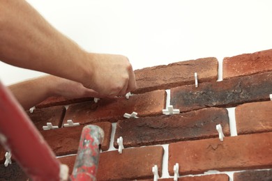 Professional builder gluing decorative brick on wall, closeup. Tiles installation process