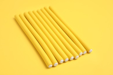 Photo of Curling rods on yellow background. Hair styling tool