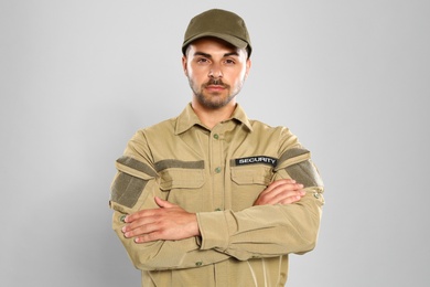 Male security guard in uniform on grey background