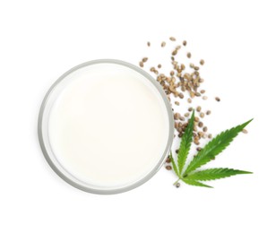 Glass of fresh hemp milk, seeds and leaf on white background, top view