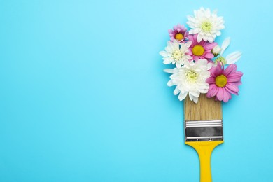 Photo of Brush painting with chrysanthemum flowers on light blue background, top view. Space for text. Creative concept