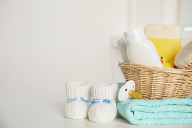 Photo of Baby booties and accessories on white table against light background. Space for text
