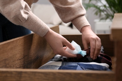 Woman putting scented sachet into drawer with clothes, closeup