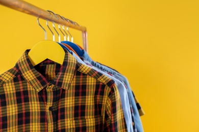 Rack with stylish children clothes on yellow background, closeup. Space for text