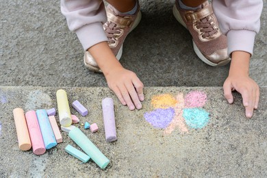 Photo of Little child drawing butterfly on curb outdoors, closeup