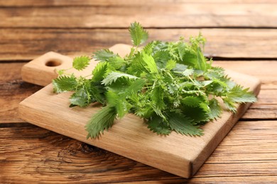 Board with fresh stinging nettle leaves on wooden table