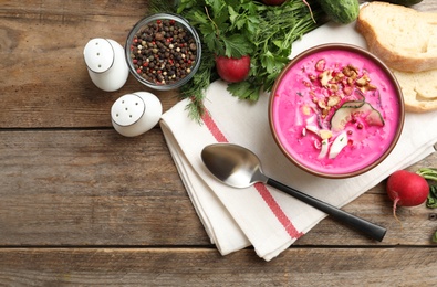 Delicious cold summer beet soup on wooden table, flat lay. Space for text