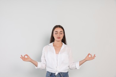 Find zen. Beautiful young woman meditating on white background