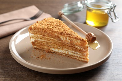 Slice of delicious layered honey cake served on wooden table