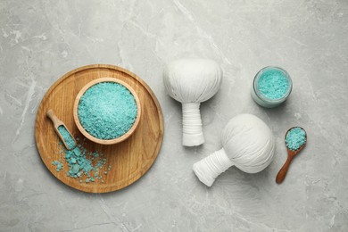 Spa herbal bags and turquoise sea salt on grey marble table, flat lay