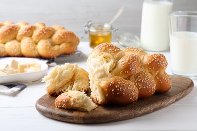 Homemade braided bread with sesame seeds on white wooden table. Traditional challah