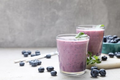Photo of Freshly made blueberry smoothie on light grey table. Space for text