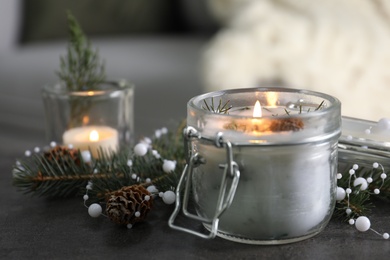 Burning scented conifer candle and Christmas decor on grey table indoors