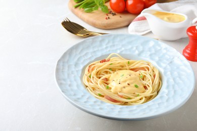 Delicious spaghetti with meat and cheese sauce on light grey table, space for text