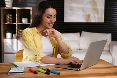 Young woman watching webinar at table in room
