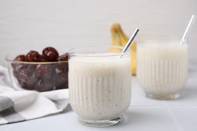 Photo of Glasses of delicious date smoothie with straws on white table