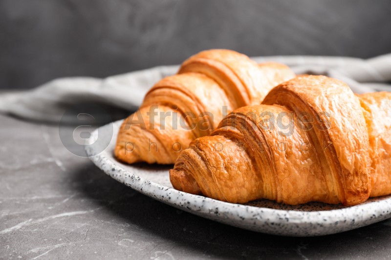 Tasty fresh croissants on brown marble table, closeup