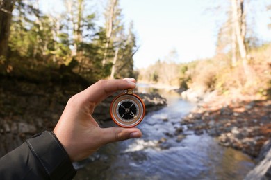 Man using compass near mountain river, closeup