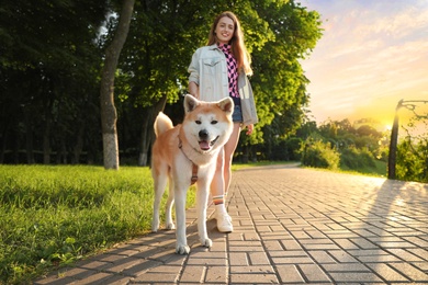 Young beautiful woman walking her adorable dog in park on sunny day