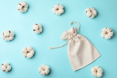 Photo of Cotton eco bag and flowers on light blue background, flat lay