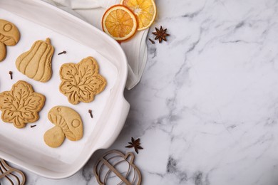 Photo of Tasty cookies and cutters on white marble table, flat lay. Space for text