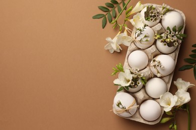 Photo of Happy Easter. Festive composition with eggs and floral decor on brown background, flat lay. Space for text