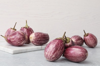 Many raw ripe eggplants on grey table