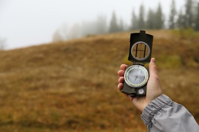 Photo of Woman using compass during journey in mountains, closeup. Space for text