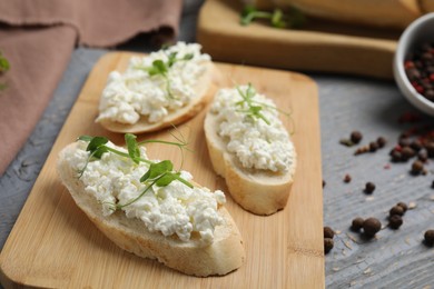 Photo of Bread with cottage cheese and microgreens on grey wooden table, closeup