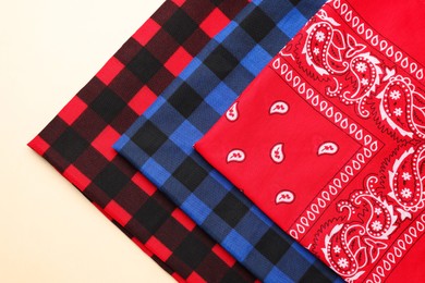 Folded bandanas with different patterns on beige background, flat lay