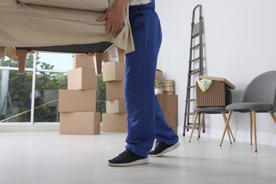 Moving service employee carrying armchair in room, closeup