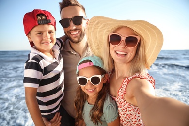 Happy family taking selfie on beach near sea. Summer vacation