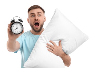 Emotional overslept man with alarm clock and pillow on white background. Being late concept