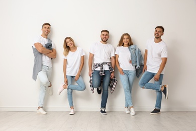 Group of young people in jeans near light wall