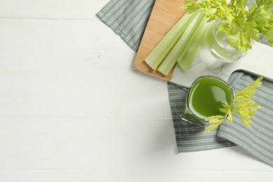 Photo of Glass of celery juice and fresh vegetables on white table, flat lay. Space for text