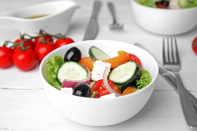 Tasty fresh Greek salad on white wooden table