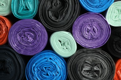Photo of Rolls of different color garbage bags as background, top view
