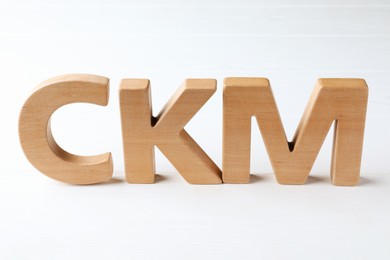 Photo of Abbreviation CKM (Customer Knowledge Management) made of letters on white wooden table