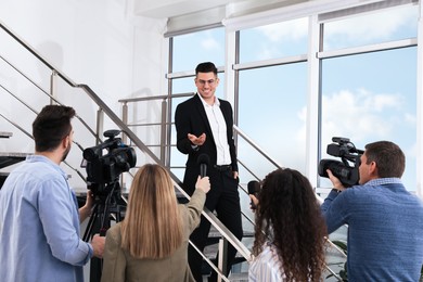Photo of Happy business man talking to group of journalists indoors