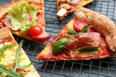 Slices of different delicious pizzas on grey wooden table, closeup