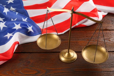 Scales of justice and American flag on wooden table