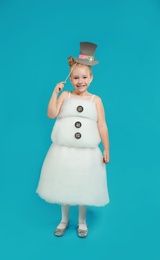 Cute little girl dressed as snowman on light blue background. Christmas suit