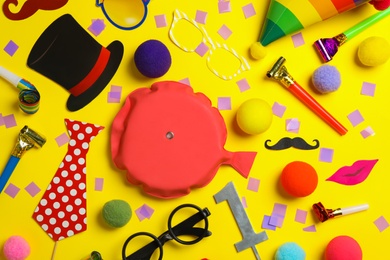 Different clown's accessories on yellow background, flat lay