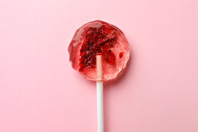 Sweet colorful lollipop with berries on pink background, top view