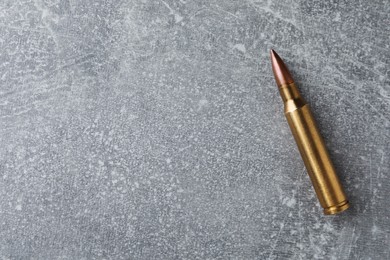 Bullet on light grey table, top view. Space for text