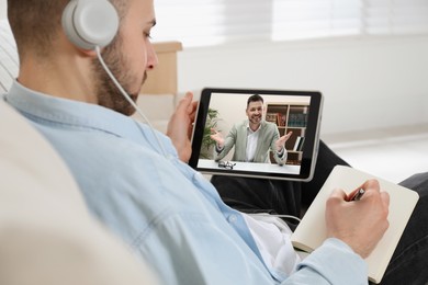 Young man with headphones and modern tablet at online lesson. E-learning